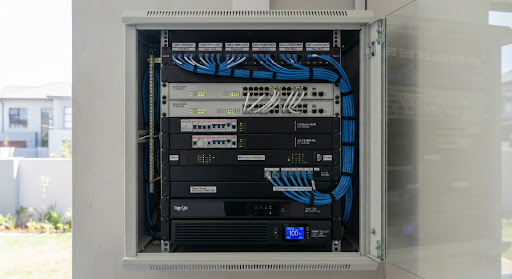 A neatly organized security electrical distribution panel with cleanly labeled Cat6 cabling, Hikvision PoE switches, backup lithium batteries, and power surge protectors installed inside an equipment cabinet in a Gauteng estate.